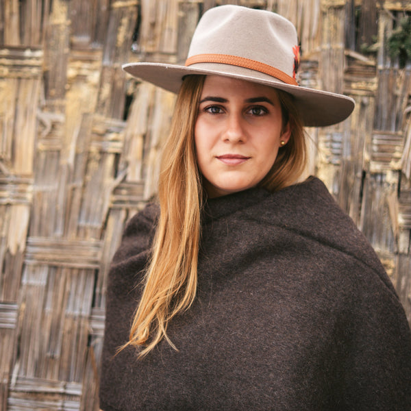Vicuña brown baby alpaca throw worn as a wrap, portrait against woven cane