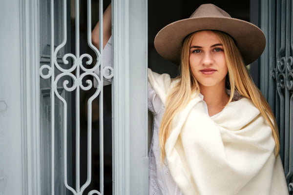 Natural cream baby alpaca throw wrapped around a model in a hacienda doorway