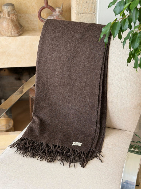 Andean brown baby alpaca throw on a chair beside Peruvian pottery