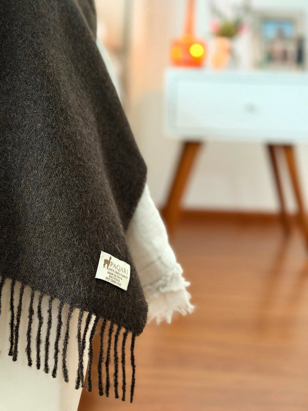 Close-up of the PAQARI woven label on the Andean throw