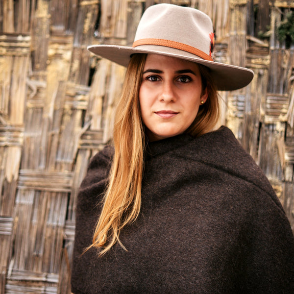 Andean brown baby alpaca throw worn as a wrap, portrait against woven cane