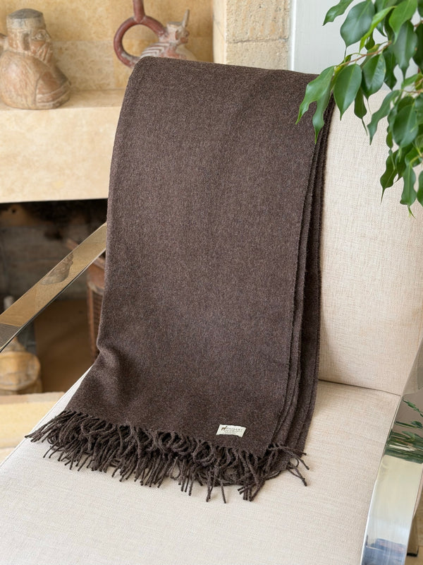 Vicuna brown alpaca throw on a chair beside Peruvian pottery