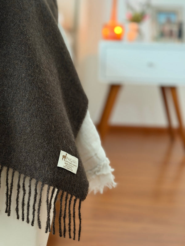 Close-up of the PAQARI woven label on the vicuna throw